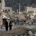 People walk on the rubble of houses destroyed by war in Taiz, Yemen.