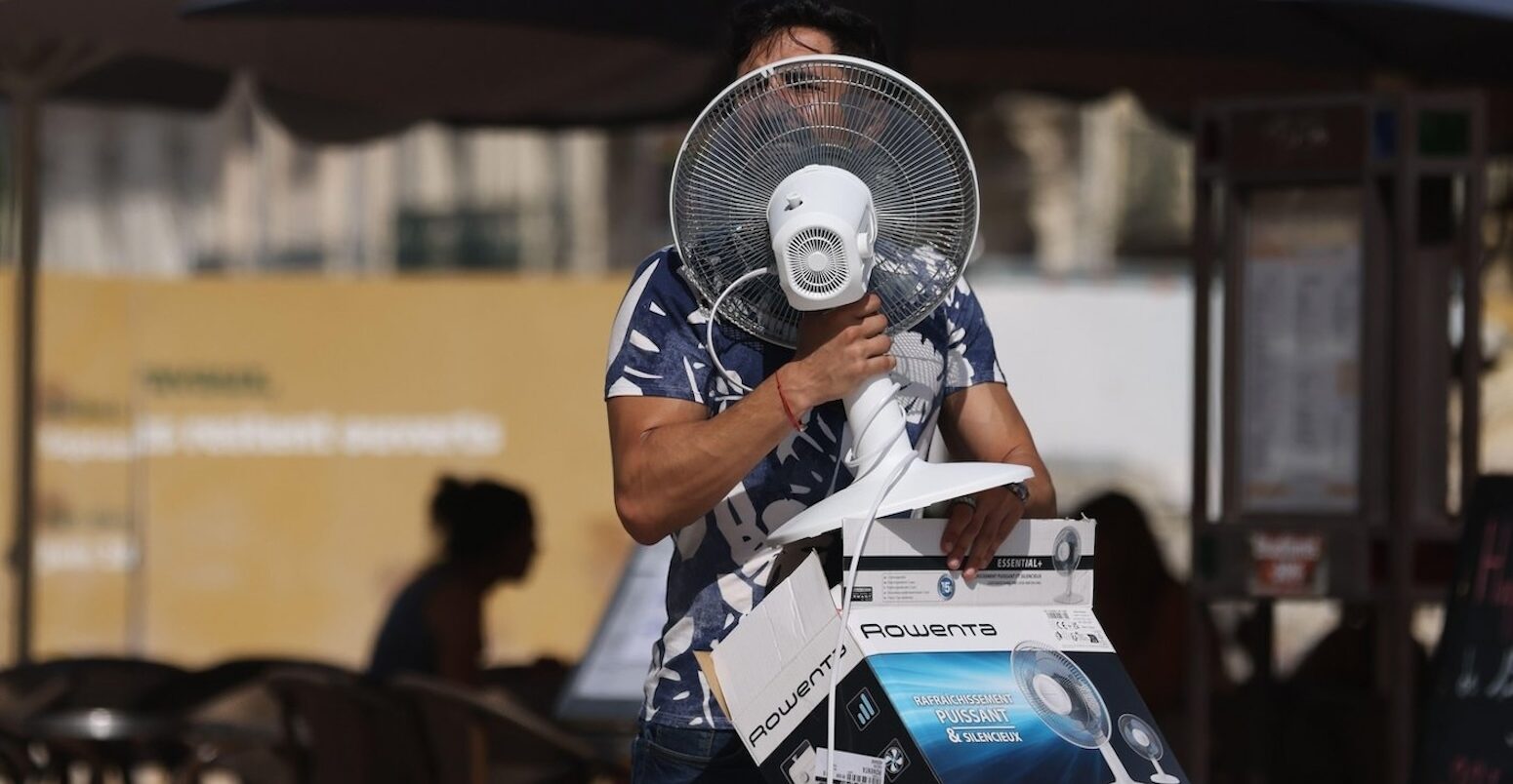 A man carries a fan as temperatures reach 38C in Montpellier, France.