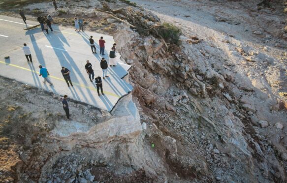 People in east Libya standing on a broken highway destroyed in recent heavy floods.