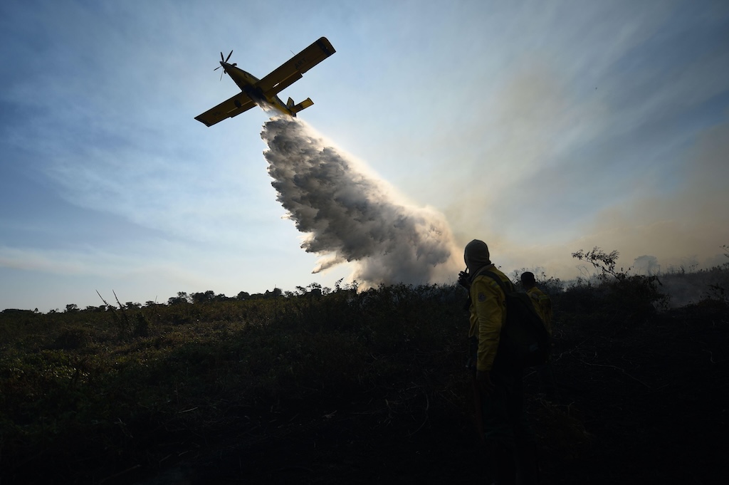 A plane dropping water as part of firefighting efforts in an area of the Pantanal affected by forest fire in Mato Grosso do Sul, Brazil on 5 July 2024.