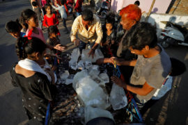 A man breaks a block of ice to distribute it among the residents of a slum during hot weather in Ahmedabad, India, April 28, 2022