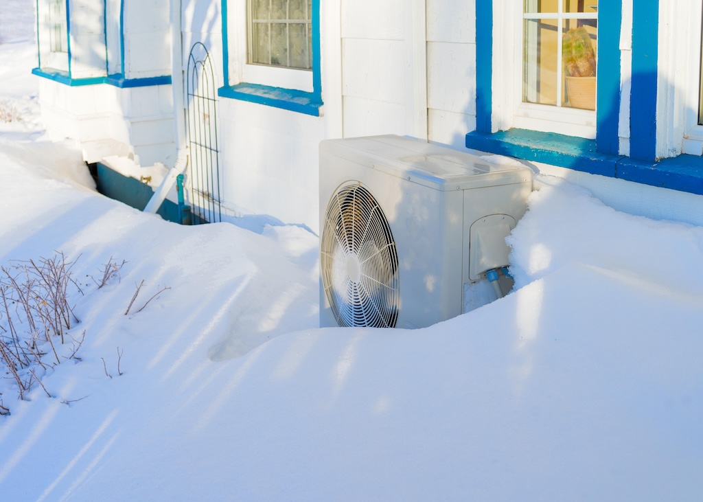 Residential heat pump covered in snow